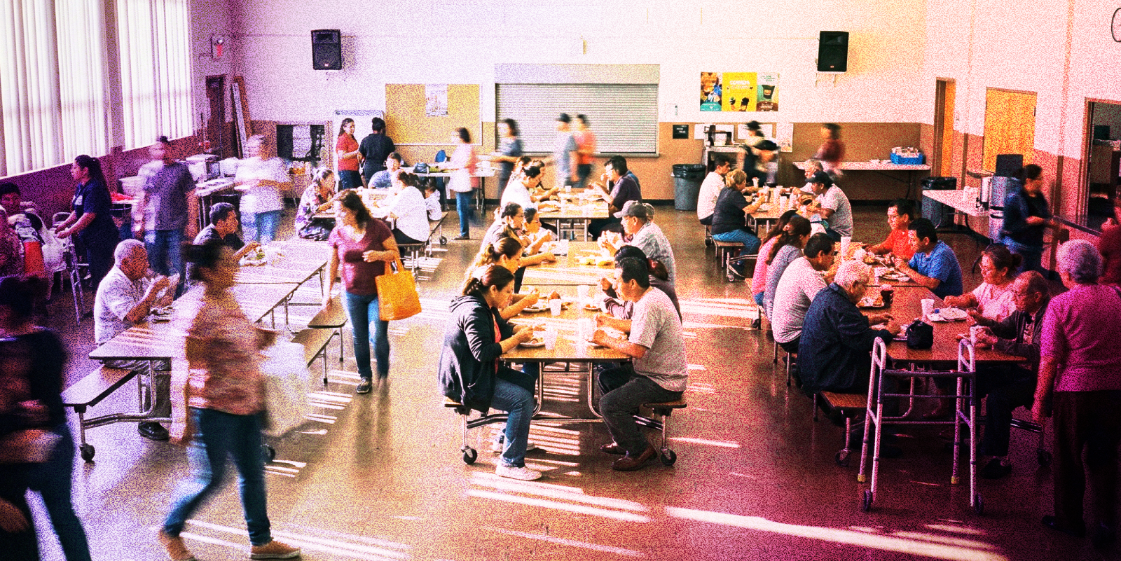 Community members eating together in a shared dining space, representing volunteer efforts like Meals on Wheels and other programs lawyers support to strengthen local communities.