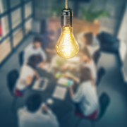 lightbulb glowing above workers in a conference room