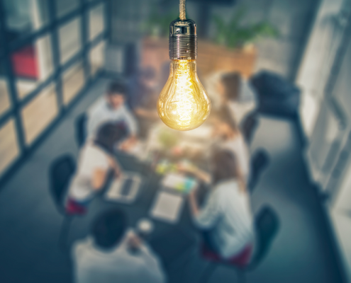 lightbulb glowing above workers in a conference room