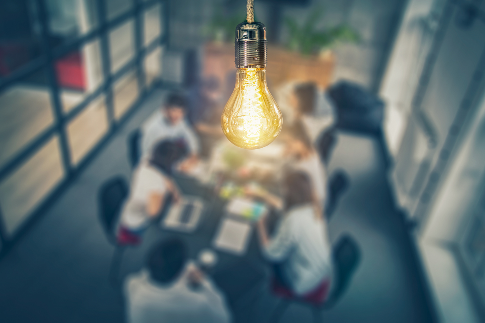 lightbulb glowing above workers in a conference room