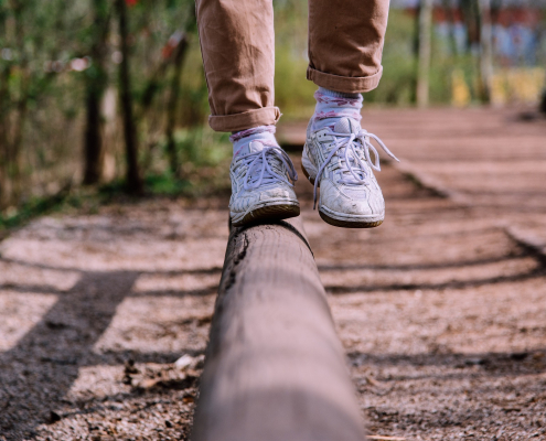person with white shoes balancing on wooden pole