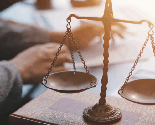 Close-up of a legal balance scale on a desk with a lawyer. working in the background.