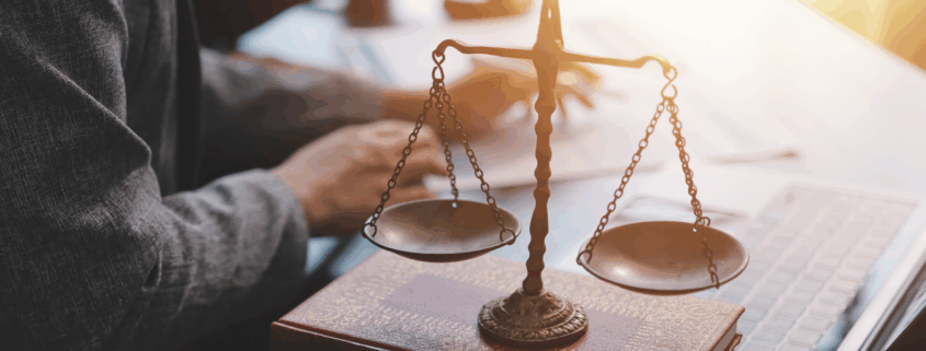 Close-up of a legal balance scale on a desk with a lawyer. working in the background.