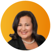 Portrait of Carolyn S., a smiling woman with dark hair wearing hoop earrings and an orange top, in a circular orange-framed photo.