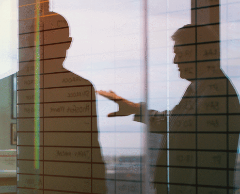 Silhouettes of two business leaders discussing strategy in an office, overlaid with planning notes, representing trust, communication, and executive decision-making for general counsel.
