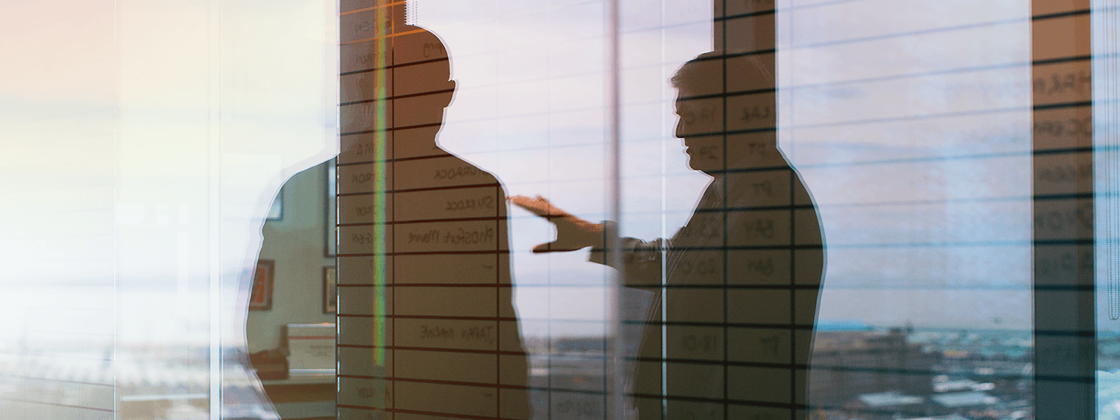 Silhouettes of two business leaders discussing strategy in an office, overlaid with planning notes, representing trust, communication, and executive decision-making for general counsel.