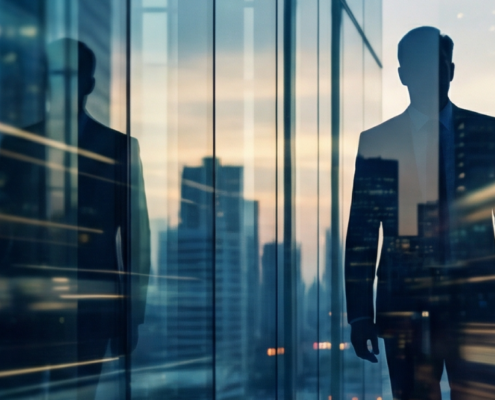 Man with their reflection showing on skyscraper windows with the city blended into the background.