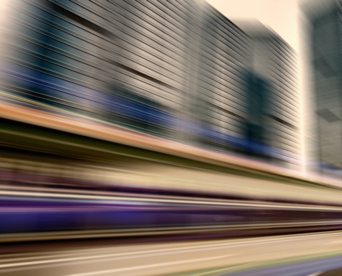 Motion-blurred view of a fast-moving city skyline and highway, symbolizing the rapid pace and steep learning curve a new general counsel faces during the first 90 days on the job.