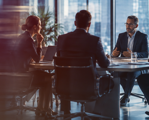 Motion-blurred photo of a legal team meeting at a glass conference table in a modern office with city skyline views.