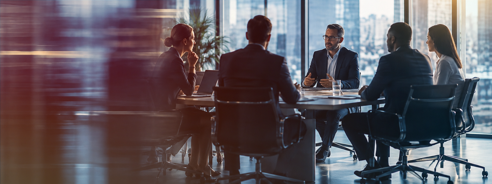 Motion-blurred photo of a legal team meeting at a glass conference table in a modern office with city skyline views.