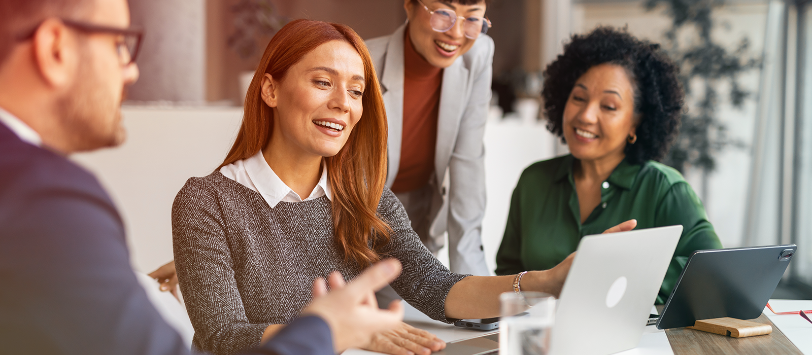 A diverse team of legal professionals collaborating around a laptop in an office setting.